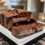Slices of moist double chocolate zucchini bread on a white plate.