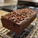 Close-up of a stack of moist double chocolate banana bread slices, with a hand taking a piece.