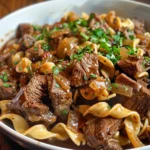 Close-up of tender beef and egg noodles in a rich gravy, served in a pressure cooker.