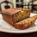 A slice of moist banana bread with melted butter on top, served on a plate.